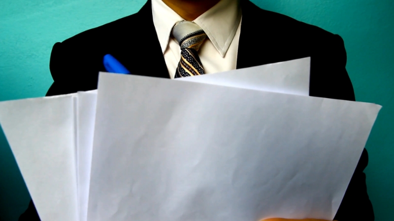 A person holds a stack of papers, preparing for a performance review