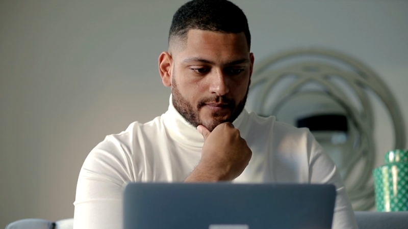 Image of a person thoughtfully working on a laptop, representing job knowledge goals for a performance review