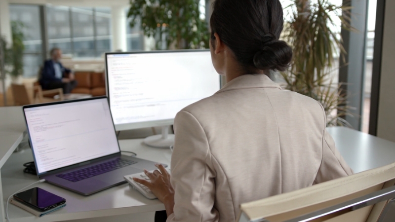 Image of a woman working at a desk with multiple screens