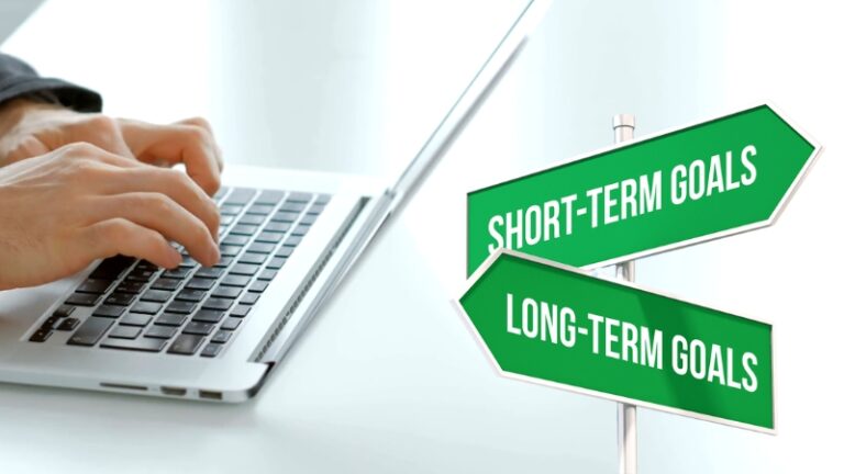 Image of a person typing on a laptop with signs for "Short-Term Goals" and "Long-Term Goals" related to a performance review