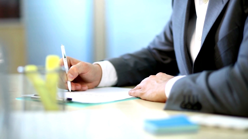 Image of a person in a suit writing notes at a desk, symbolizing the importance of setting education goals for professional development