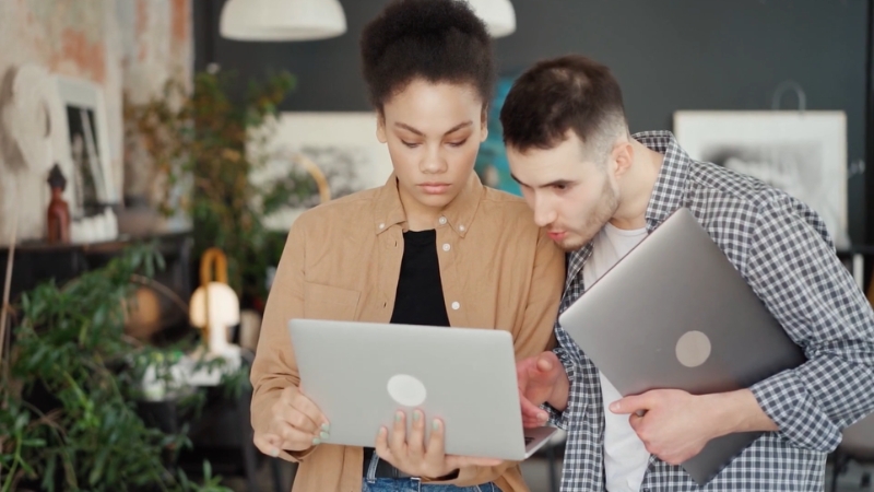 Two coworkers use a laptop to stay connected and engaged with HRMS tools