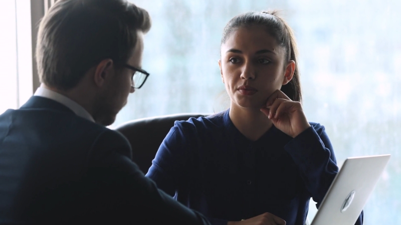 A businesswoman listens to a man in a suit