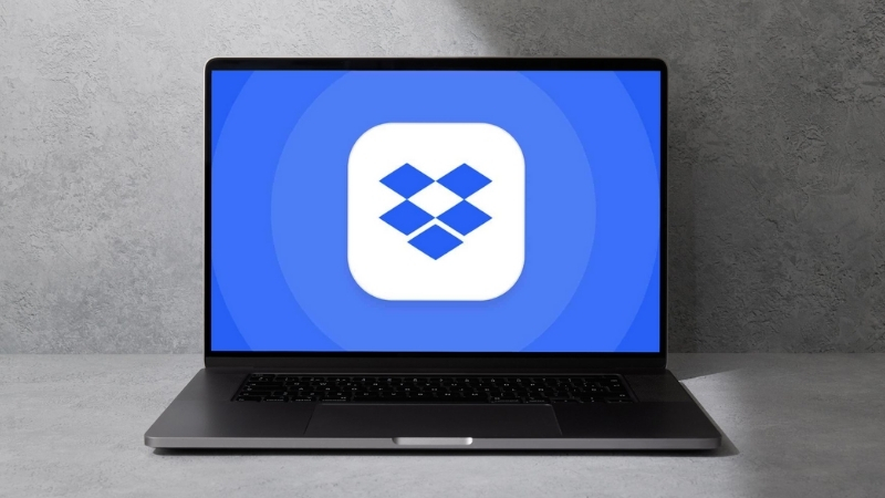 A laptop displays the Dropbox logo
