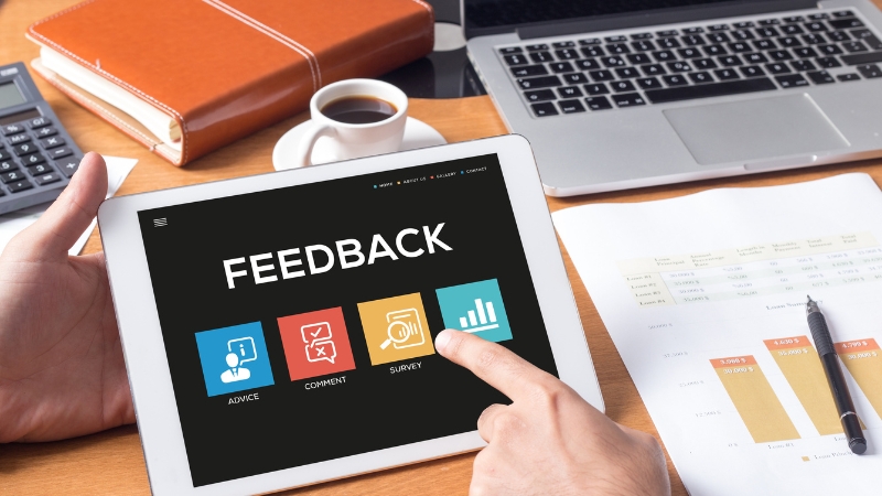 A person using a tablet showing feedback options like advice, comments, and surveys at a work desk
