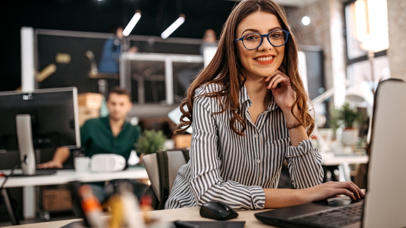 Young woman from Gen Z working confidently at her desk in a modern tech office