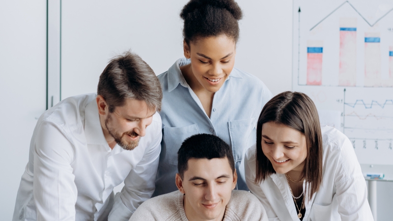 A diverse group of young professionals collaborating on a project in a modern office setting