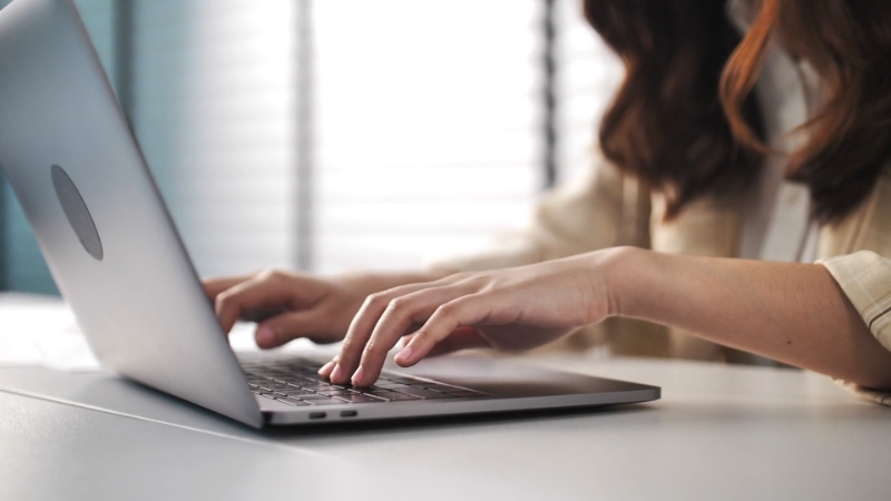 Close-up of a woman typing on a laptop, representing the hands-on use of modern HRMS software for daily HR tasks