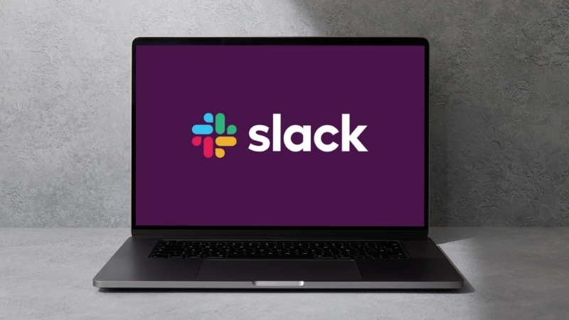A laptop screen shows the Slack logo, highlighting one of the top free productivity apps for team communication