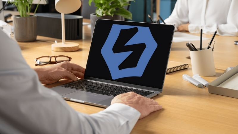 A person working on a laptop displaying the Spidergap logo, in a modern office setting