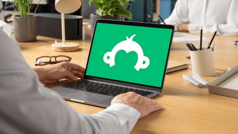 A person working on a laptop with the SurveyMonkey logo displayed on the screen in a bright office setting