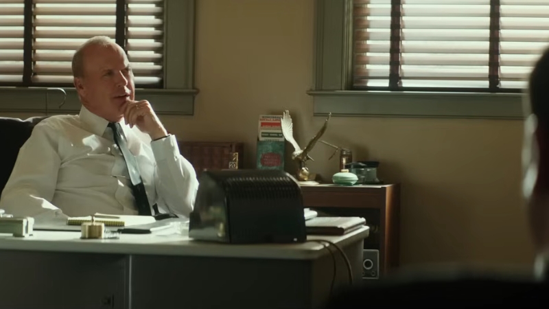 A business executive sits at his desk during a tense conversation in a scene from The Founder (2016)