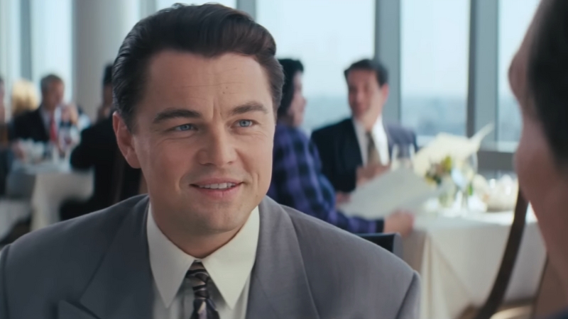 Jordan Belfort smiles across the table during a business lunch in a scene from The Wolf of Wall Street (2013)