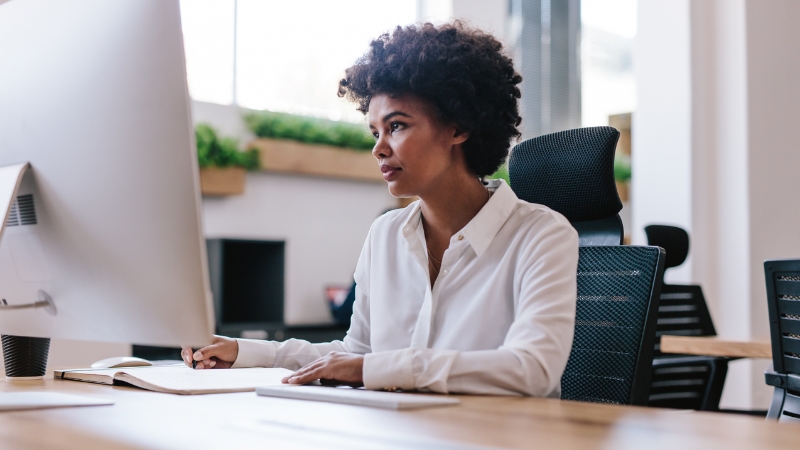 A focused professional works at her desk using HR software, highlighting how HRMS adoption supports modern workplace efficiency