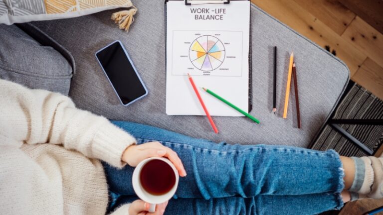 A person sits with a cup of tea and a worksheet labeled "Work to Live or Live to Work" while planning their work-life balance
