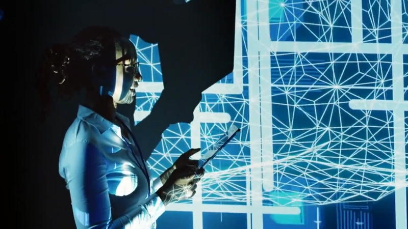 Woman holding a tablet stands before a digital network display, representing the next wave of AI in HR