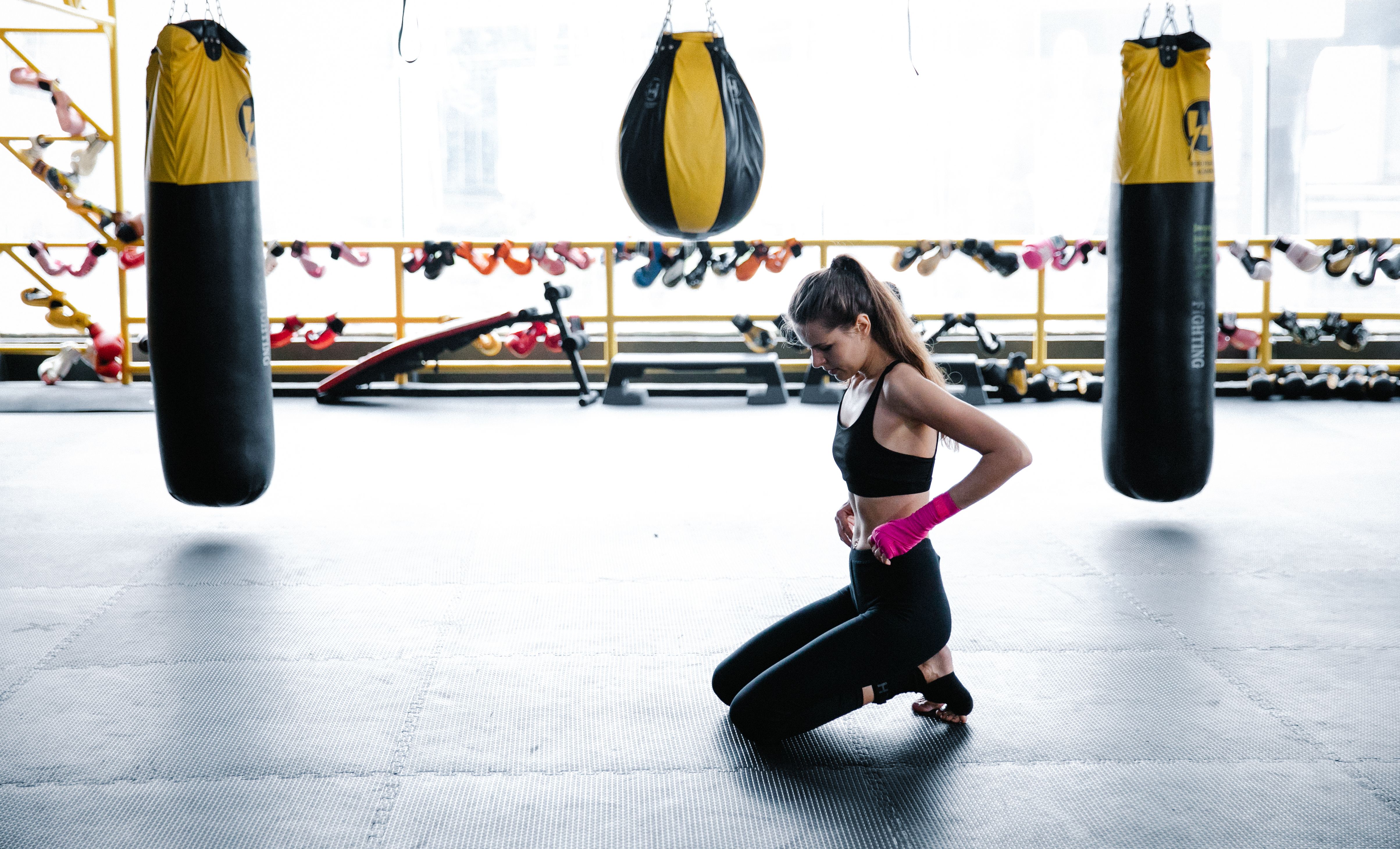 Woman gets ready for a boxing workout with gloves and gym equipment.