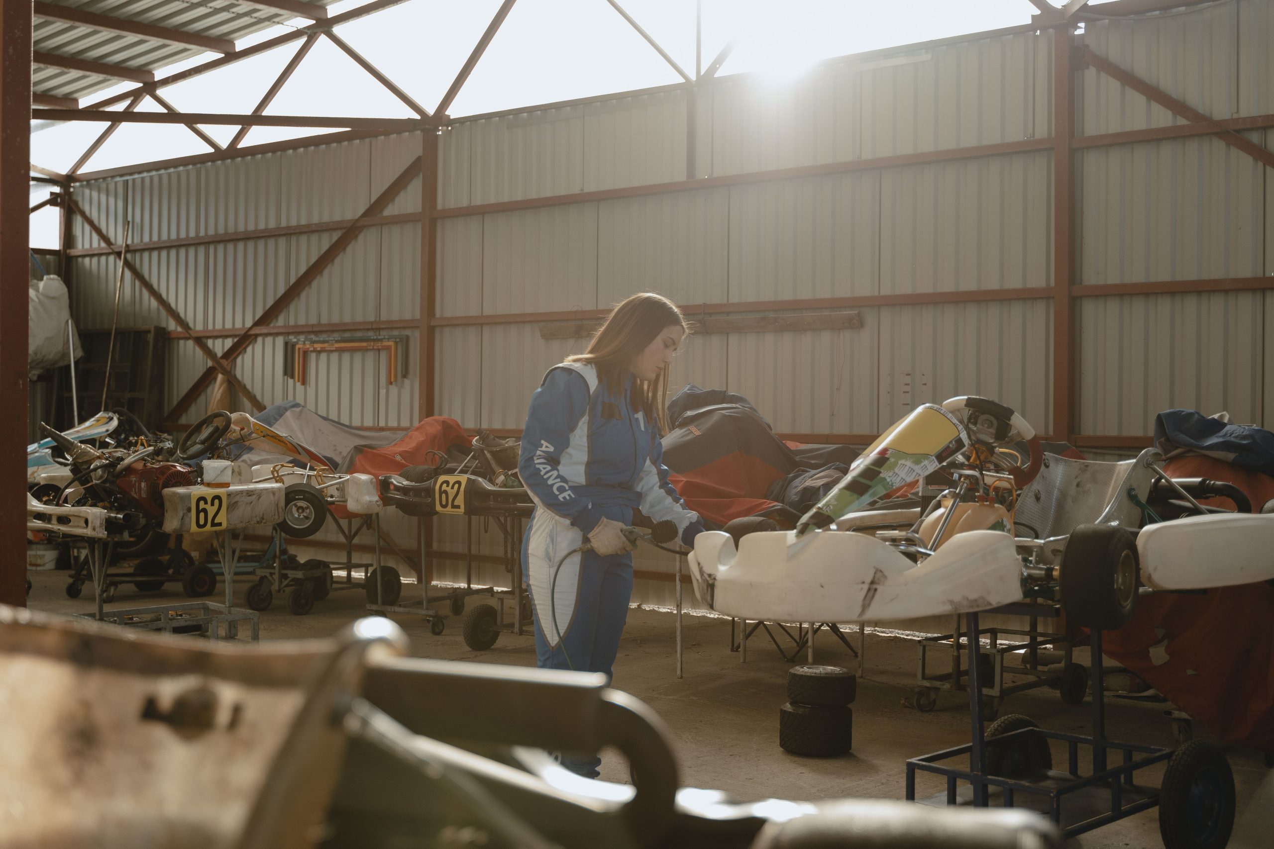 Female go-kart racer prepares her vehicle in the garage before a track experience.